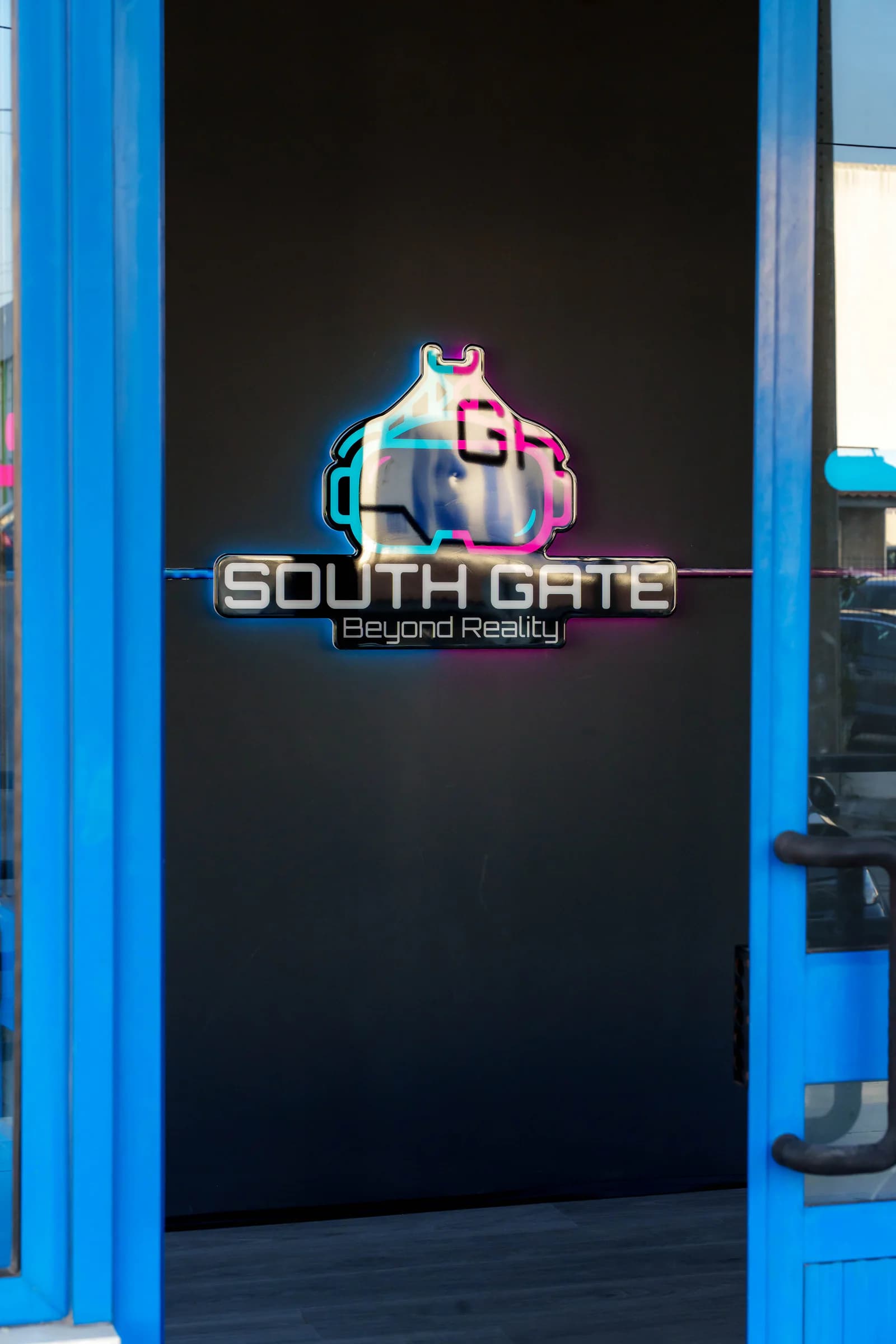 Logótipo iluminado da South Gate, "Beyond Reality", na parede preta do átrio de entrada
